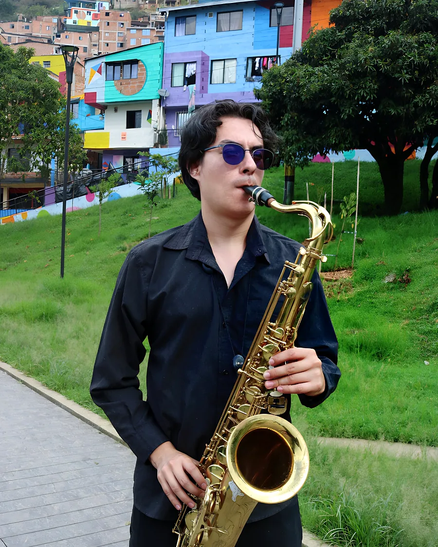 Walter Agudelo Múnera, Walamort, tocando el saxofón tenor frente a las casas de colores de Medellín